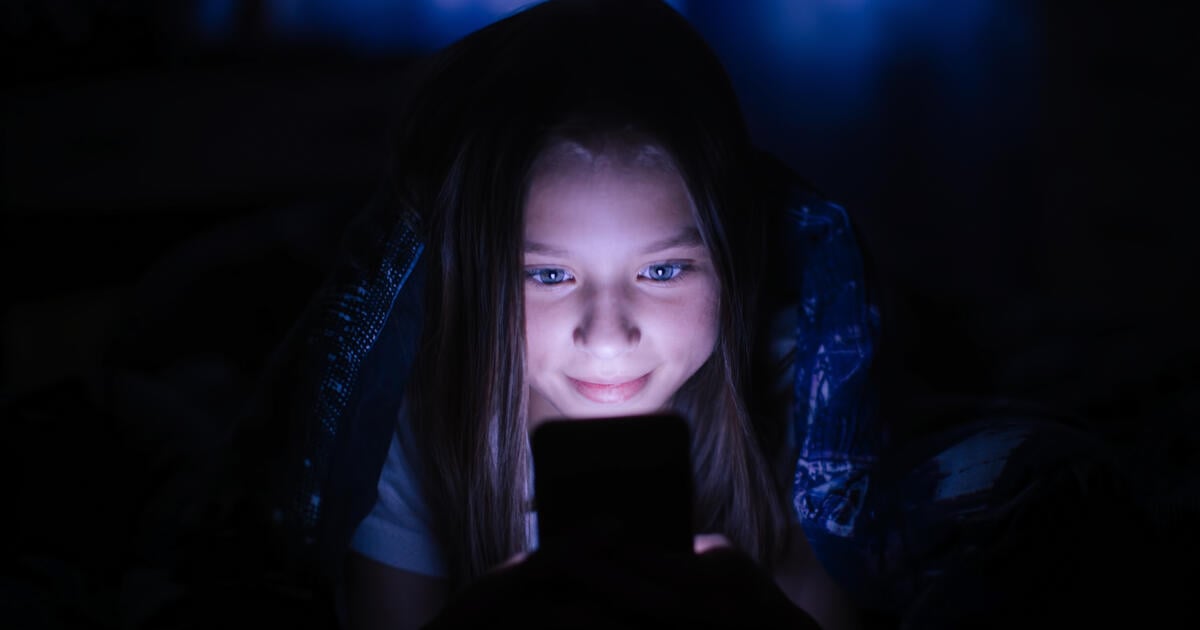 Girl with face illuminated by smartphone