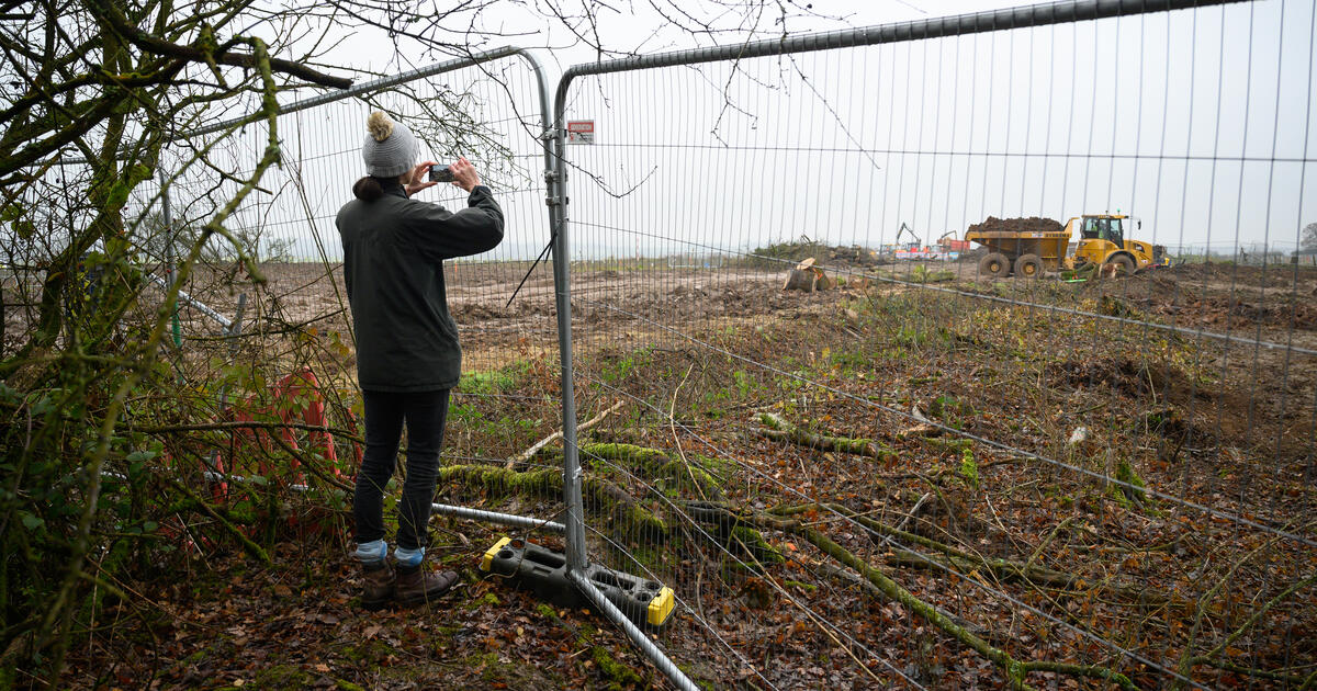 Person photographing a construction site behind a temporary fence