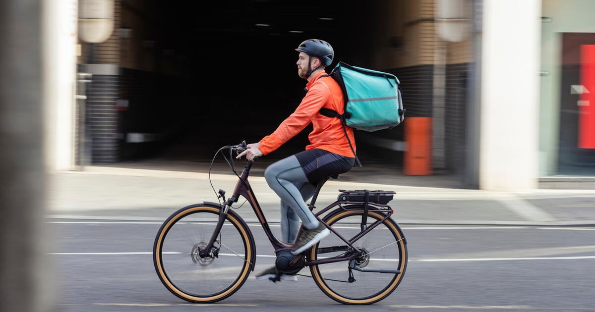 Cyclist delivering food with backpack riding through city street