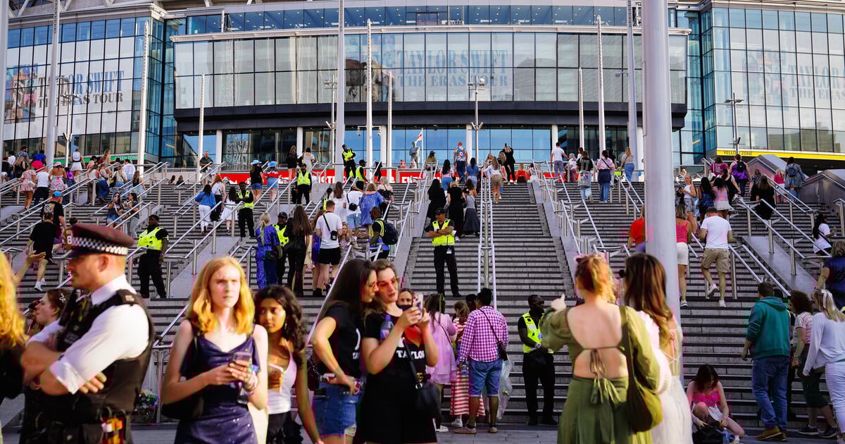 Crowds on steps outside a glass-fronted venue with visible security presence
