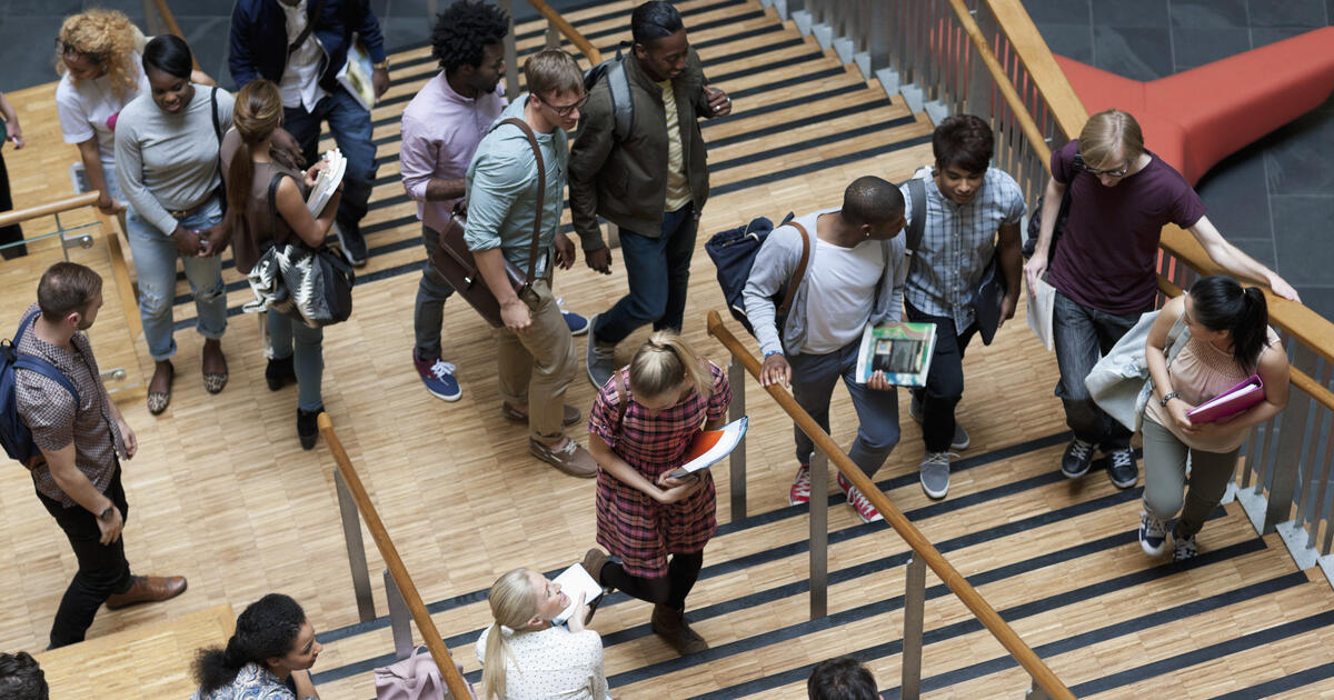 People moving up and down wooden stairs in a modern building