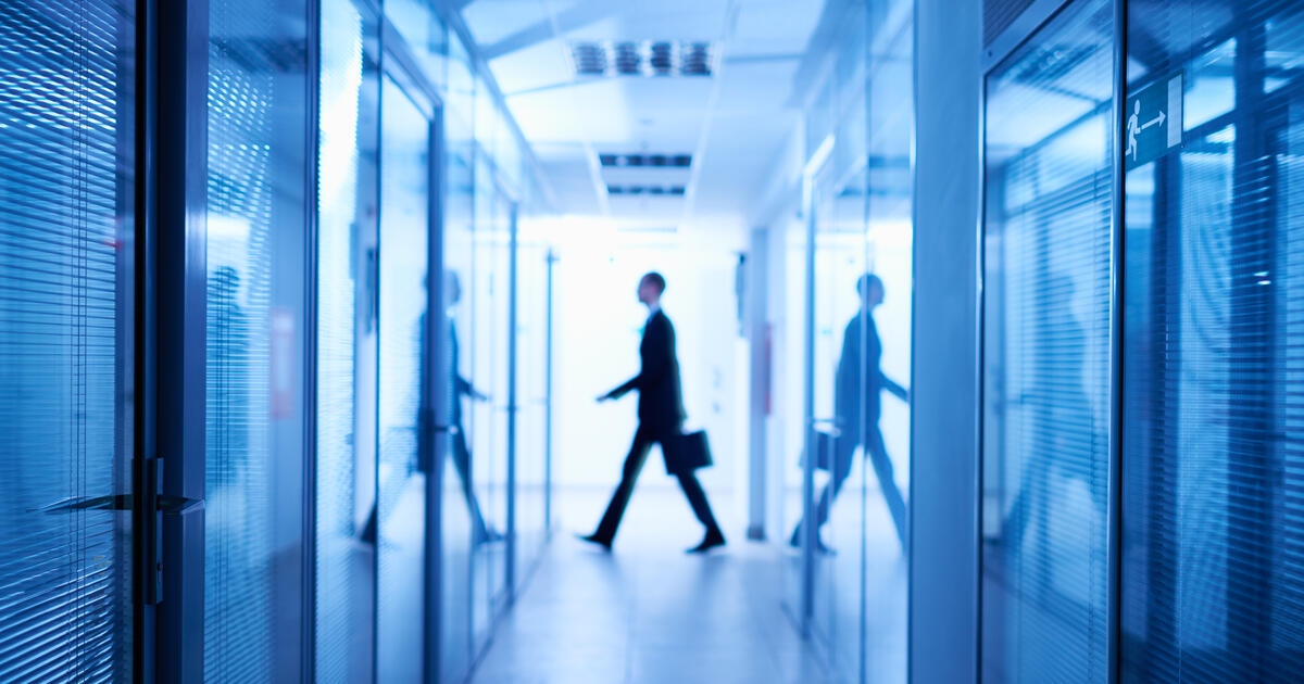 Silhouette of businessman with portfolio walking in background, dark long corridor of spy organization