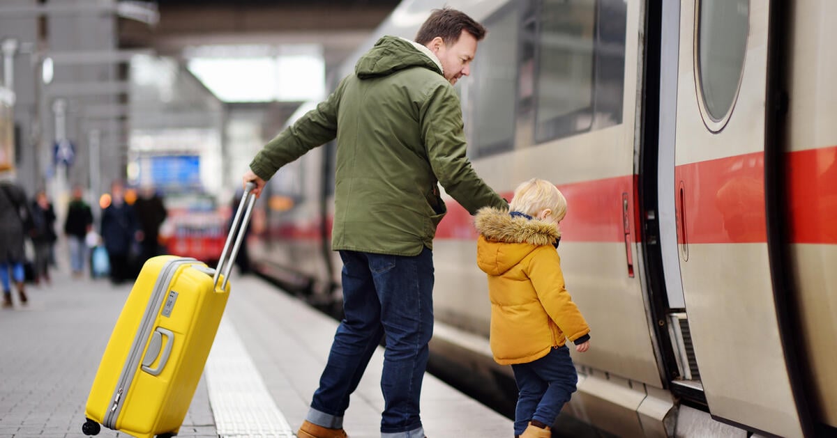 Little boy and his father go in express train on railway station platform
