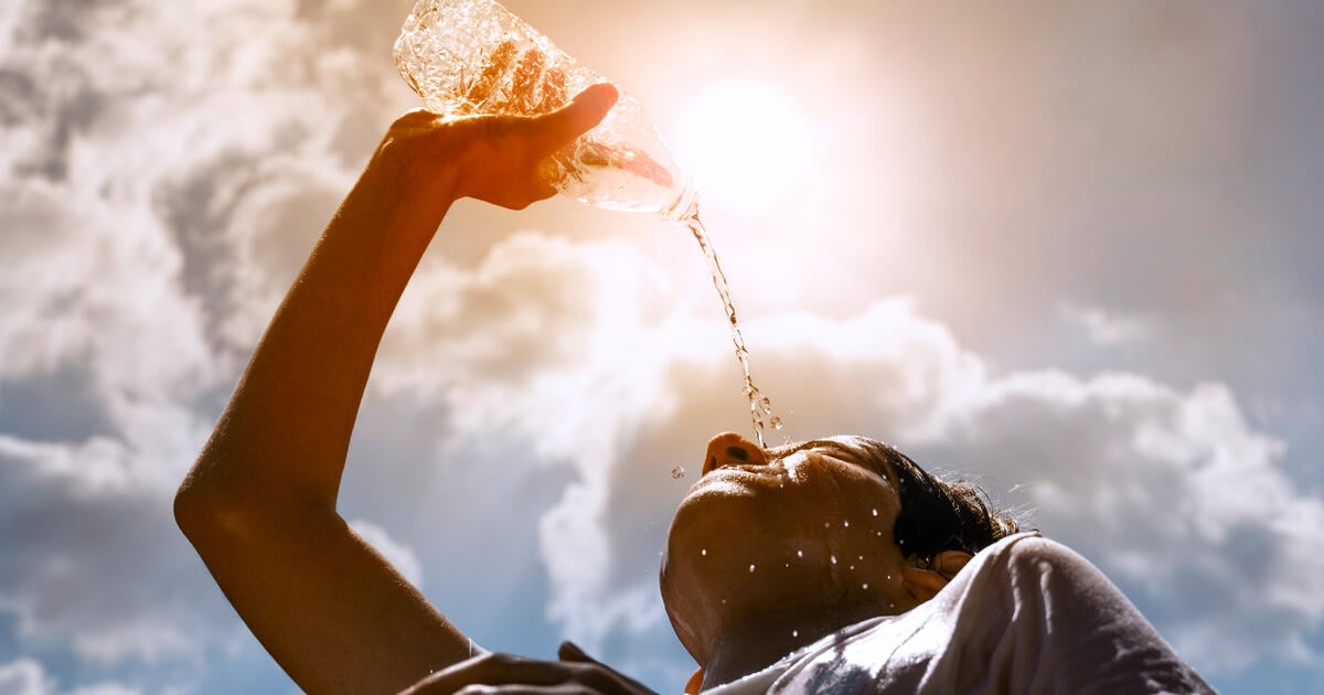 Young woman drinking water under the summer sun