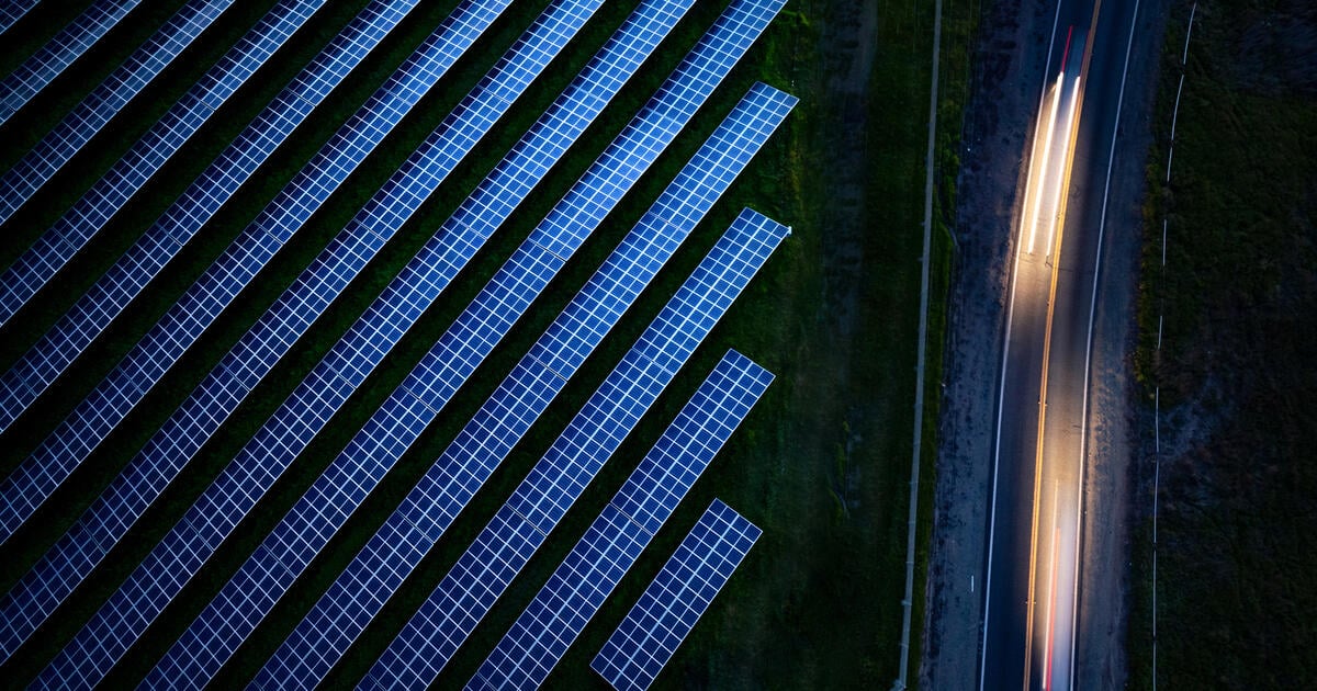 Aerial stock photo, looking down at blurred highway traffic with solar panels at sunset and blue hour