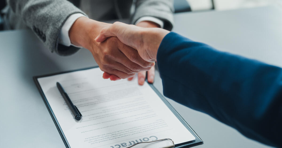 Close-up of young Asian businessmen shaking hands after signing a successful partnership agreement in modern office. Business Deal, Contract Signing, Partnership Agreement Concept.