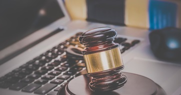 Law legal concept photo of gavel on computer with legal books in background