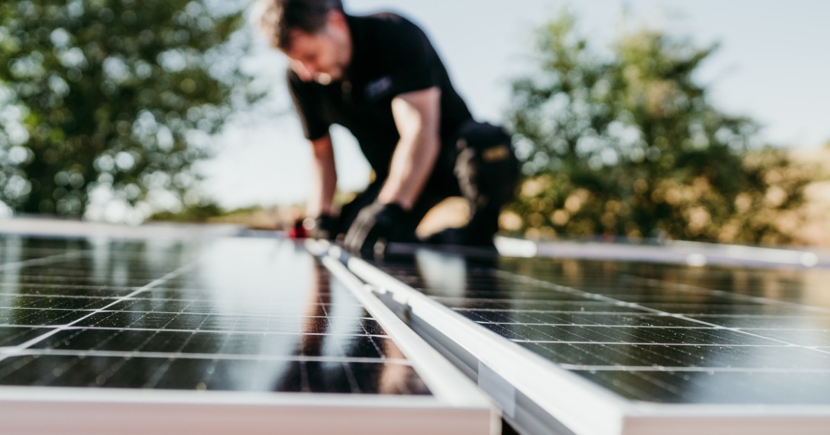 Technician installing solar panels on roof