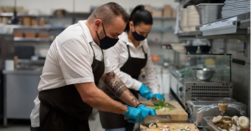 chef-and-cook-with-face-masks-cutting-vegetables-indoors-in-restaurant-kitchen-coronavirus seo