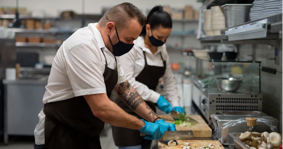 chef-and-cook-with-face-masks-cutting-vegetables-indoors-in-restaurant-kitchen-coronavirus seo